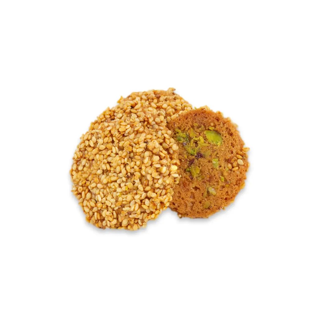 This is a close-up photo of Barazek, a traditional Middle Eastern sesame and pistachio cookie with a crunchy sesame coating on one side and a pistachio-studded center on the other.