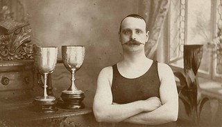 Man in a swimming costume standing with two tr...