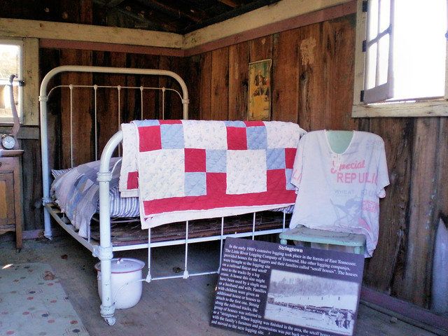 White painted iron bed with homemade quilts and shirt made from flour sacks