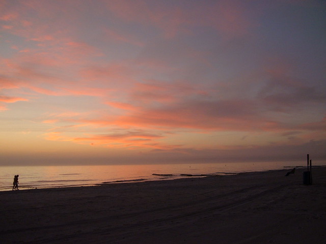 photo of sunset over Gulf of Mexico with pink sky and silhouetted couple walking