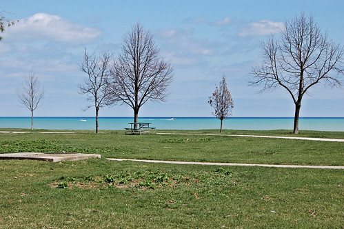 View of lake with greening grass and two layers of blue in the water