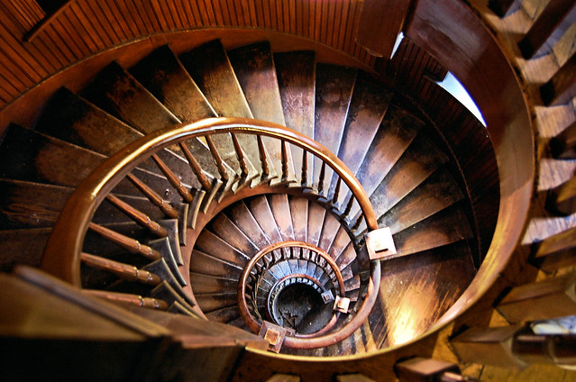 View down wooden oval spiral stairs that are well worn.