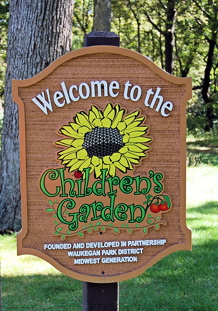 Sign before an area of raised gardens that were planted by children groups