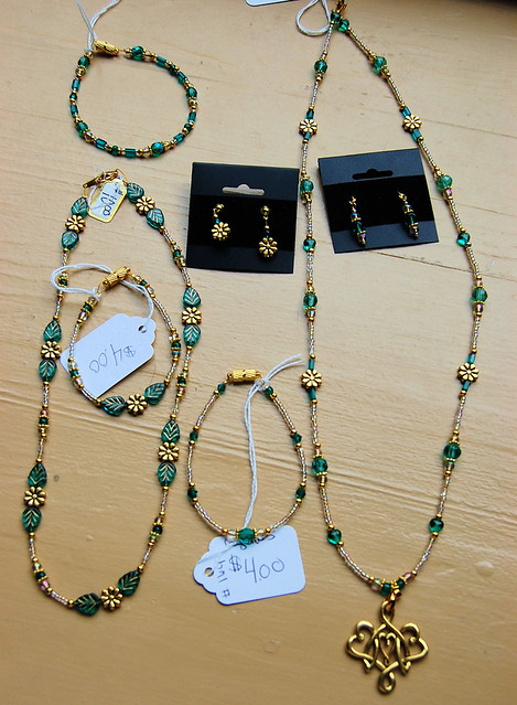 A collection of necklaces, earrings, and bracelets featuring gold tones with Aquagreen  glass