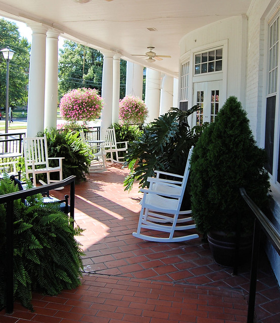 brick porch with white rockers and lovely potted plants.