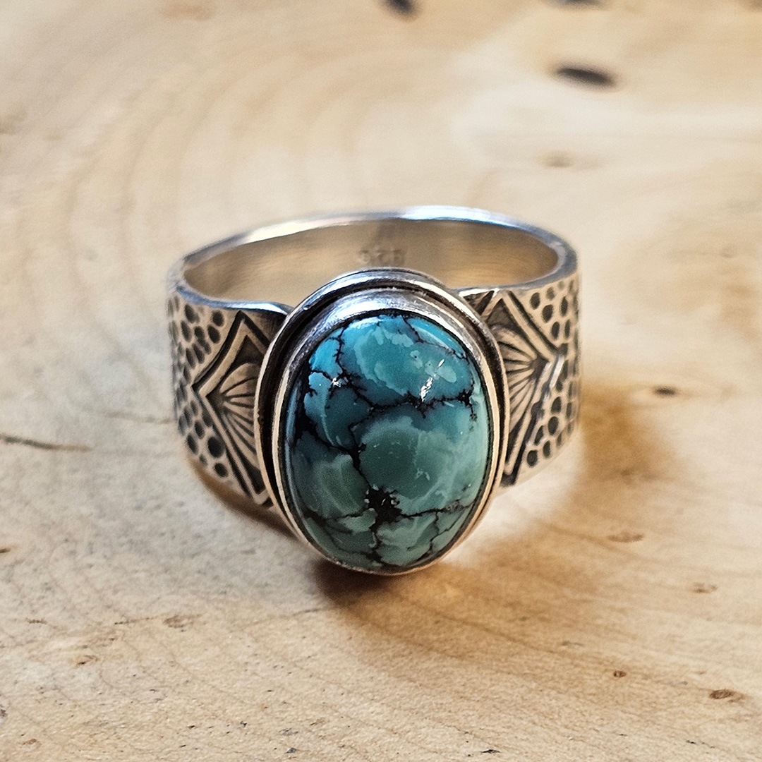 A stamped Hubei turquoise ring on a wood surface