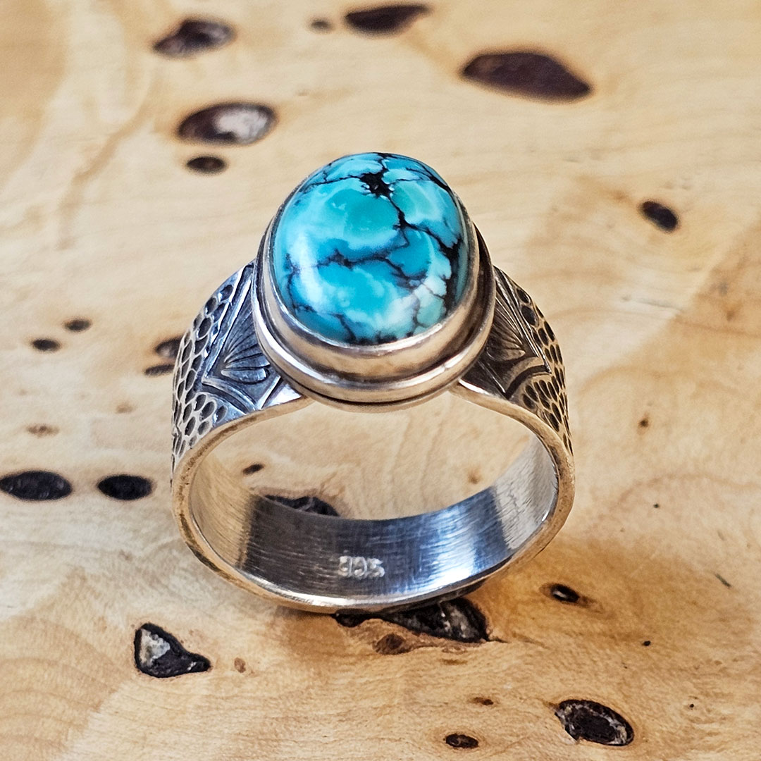 A stamped Hubei turquoise ring on a wood surface