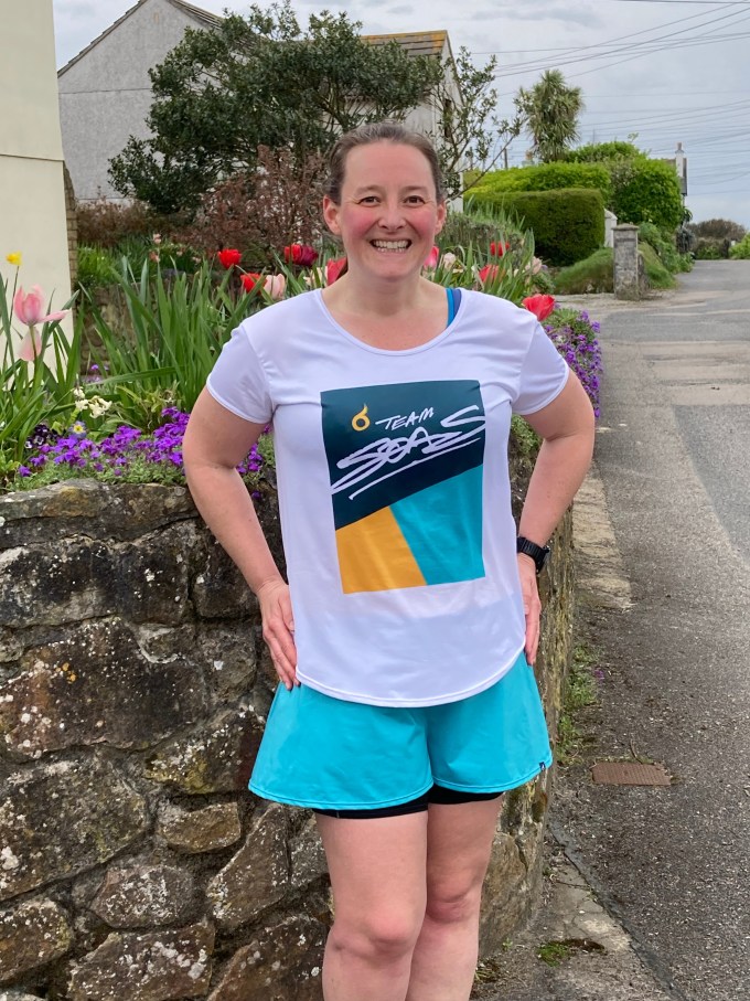 Tamsyn wearing a teal, turquoise, yellow and white Team SOAS t-shirt. She is smiling.