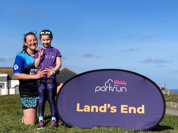 Tamsyn and M by the Land's End parkrun sign.