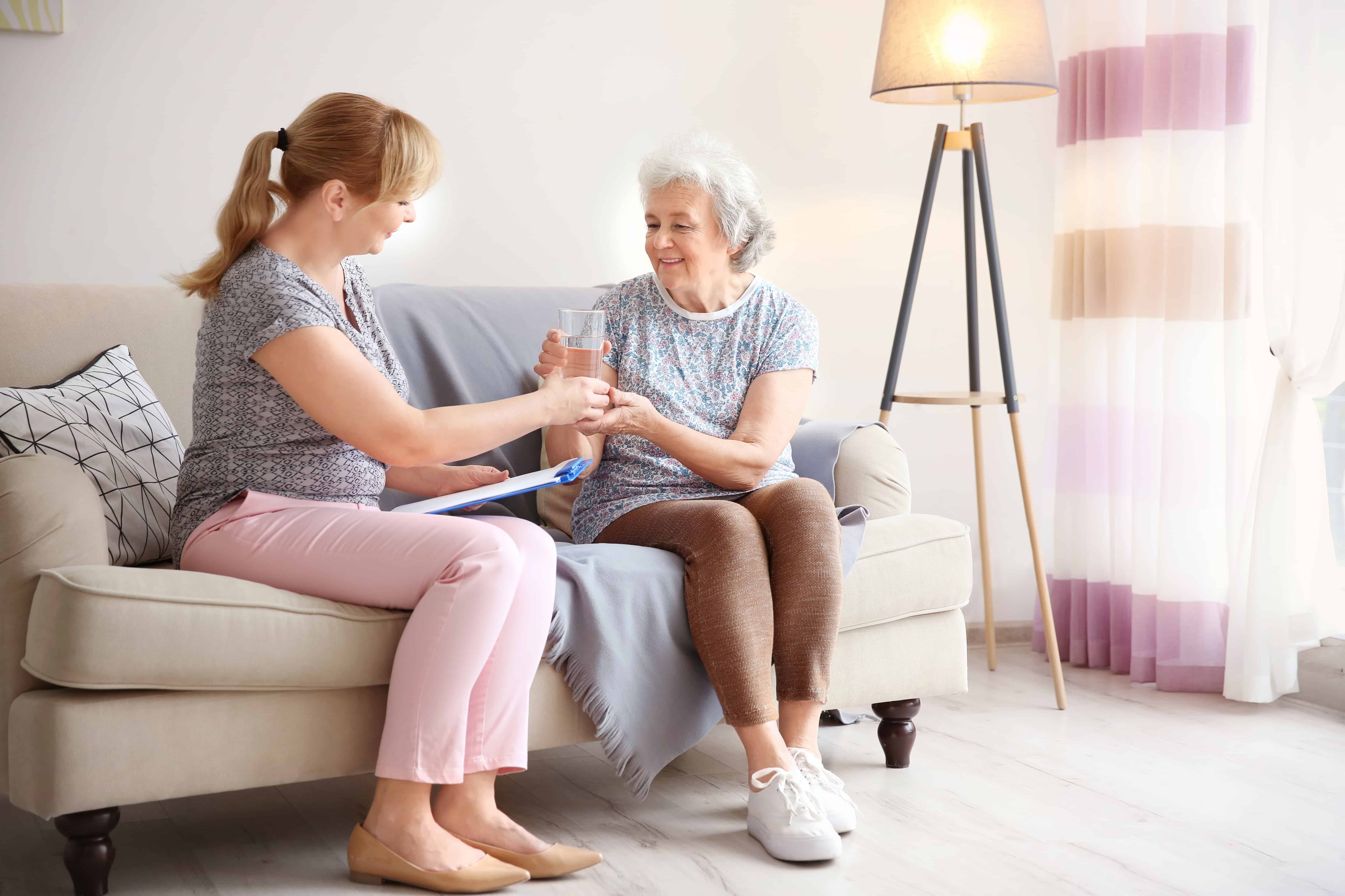 a female caregiver helps her senior client with medication
