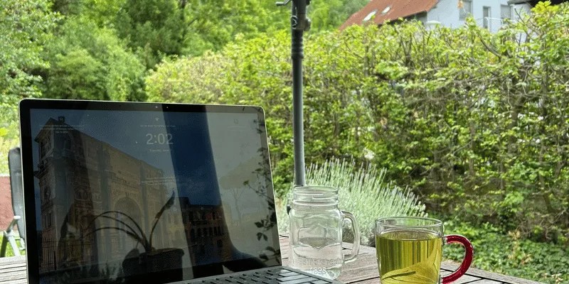 Laptop and cup of tea outside under an umbrella