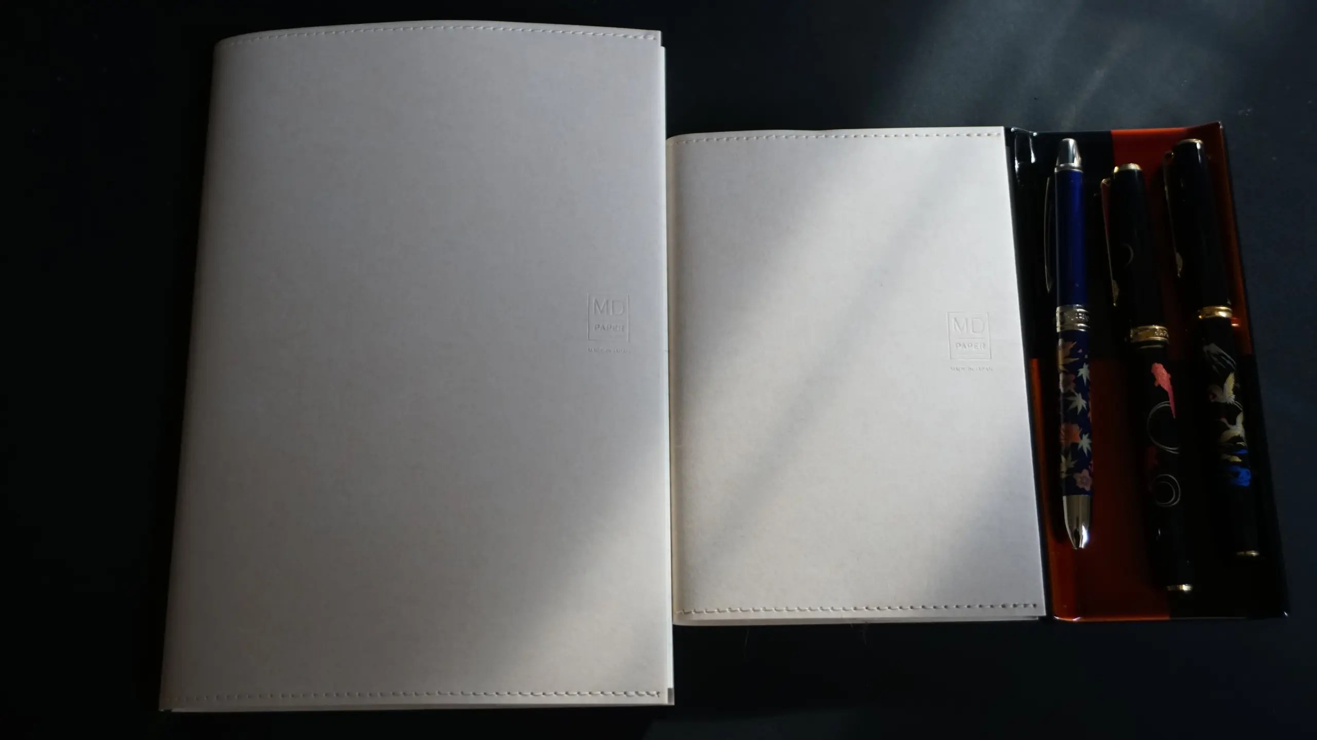 Photo of two different sized MD Notebooks next to a Yamada Heiando pen tray with three different pens from Platinum.