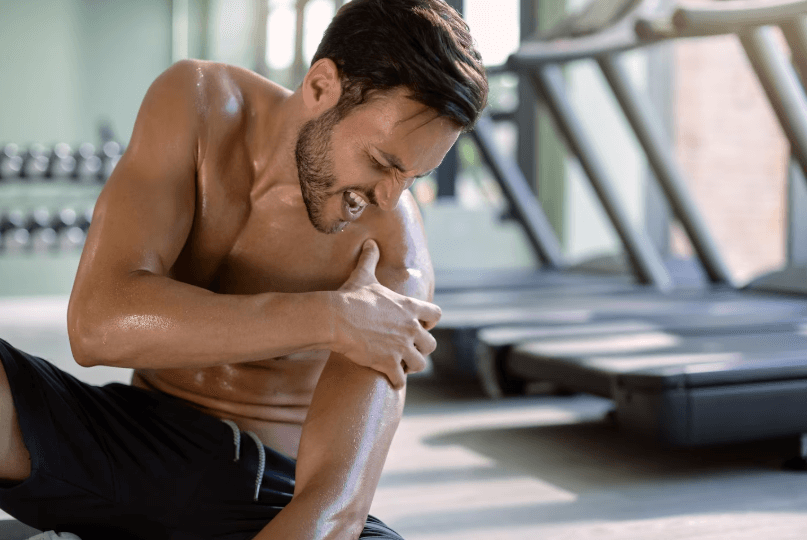 athete with shoulder pain sitting in the gym