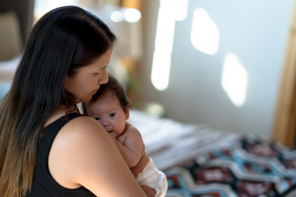 A woman holding her baby closely in the bedroom --Une femme tenant son bébé près d'elle dans la chambre