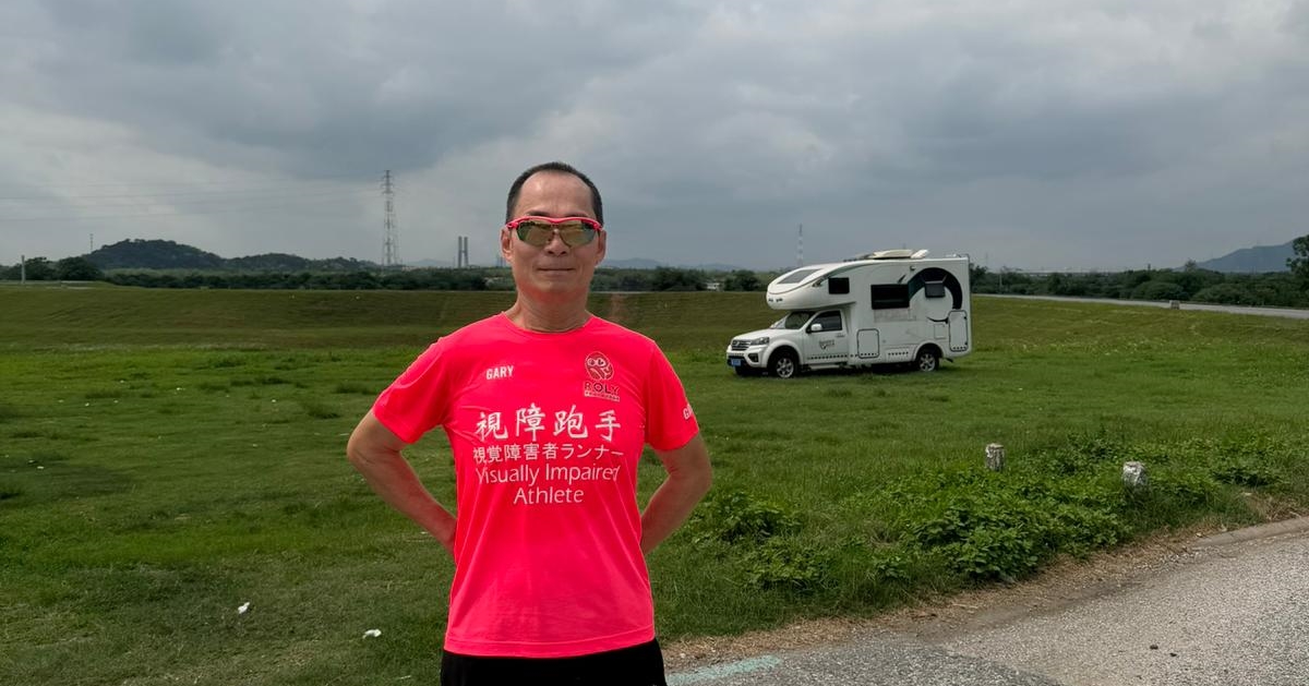 視障跑者與領跑員手拉繩索，在眾人簇擁下邁步奔跑