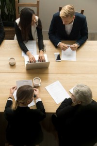 Diverse plaintiff attorneys lean over legal documents at a conference table, intensely discussing how non-recourse financing could help take on their next big case, with one lawyer pointing to projected litigation costs on a laptop screen