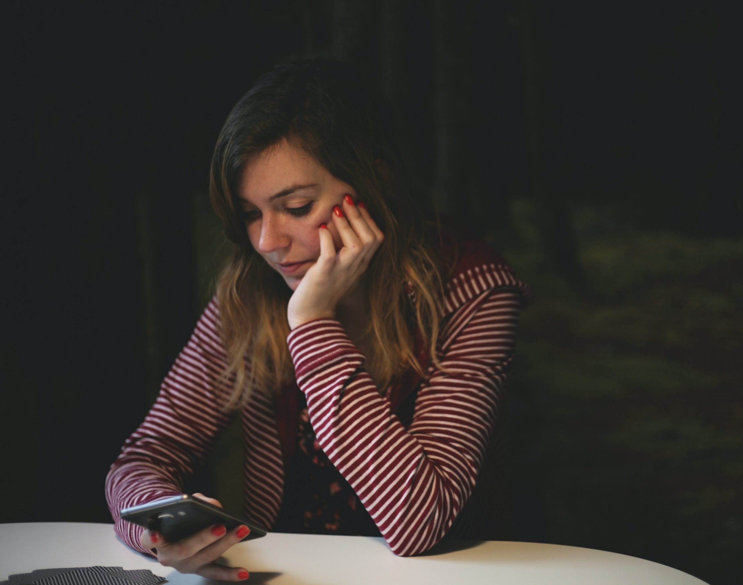 Girl looking down at her phone wondering, Do I Have An Addiction?