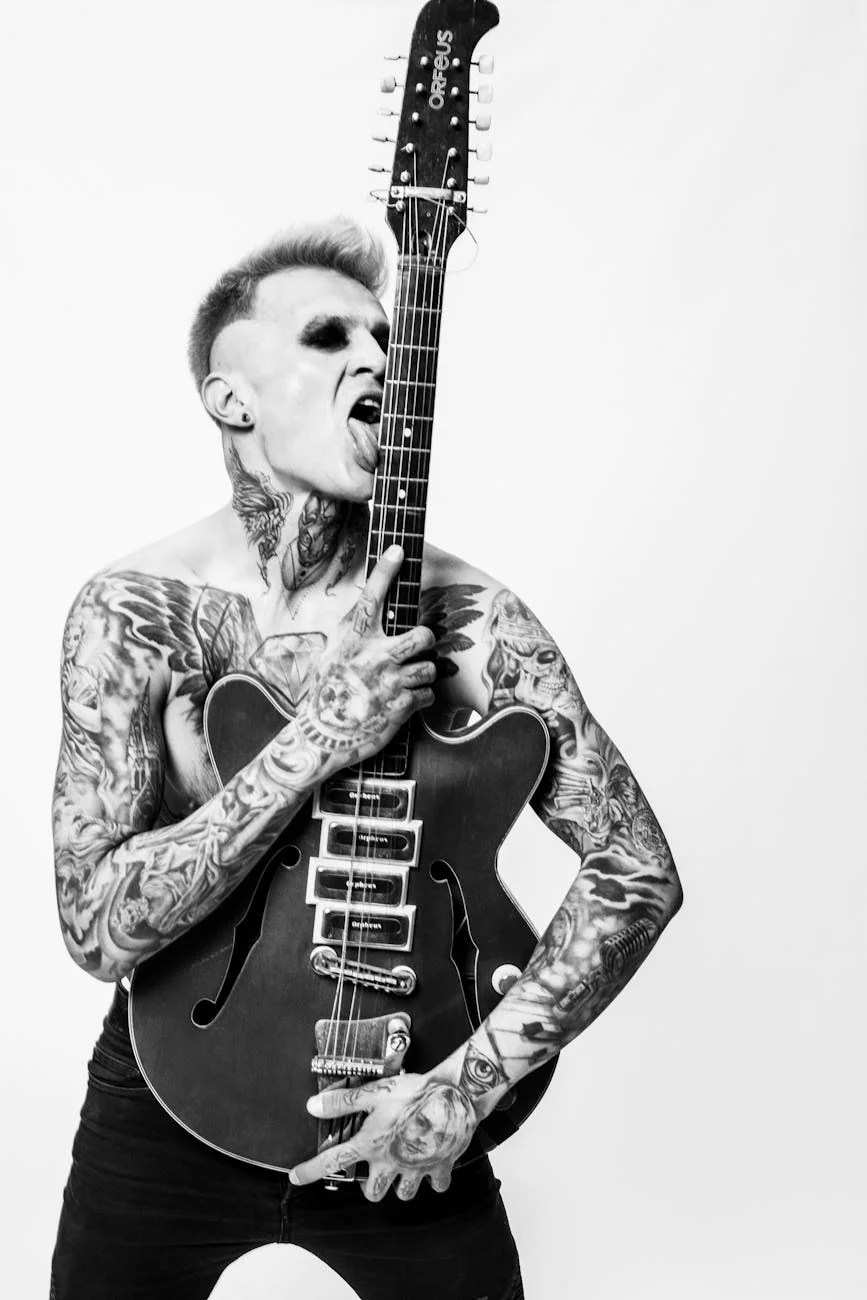 grayscale photo of tattooed man licking an electric guitar