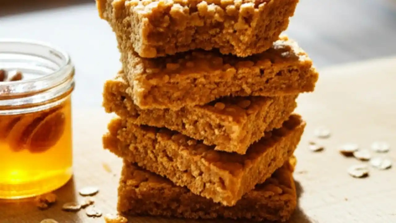 A stack of perfectly chewy and golden authentic British flapjacks on a wooden serving board, ready to be eaten.
