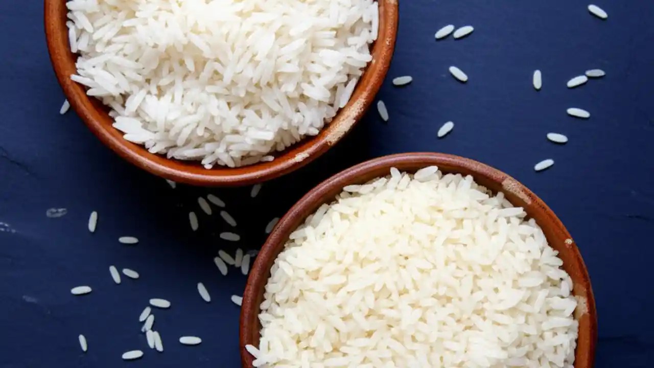 Two white bowls on a dark wooden table, one filled with long-grain, fluffy Basmati rice and the other with standard white rice, showing the difference in texture.