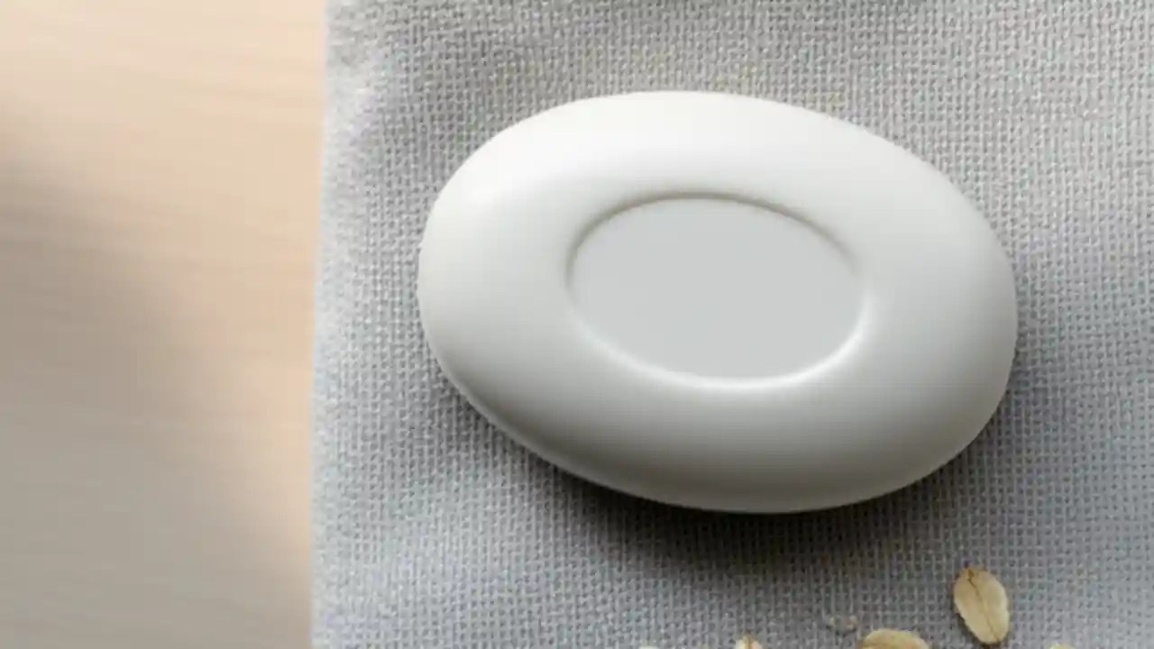 A gentle, natural bar of oatmeal soap on a white dish, a recommended type of soap for soothing itchy and sensitive skin.