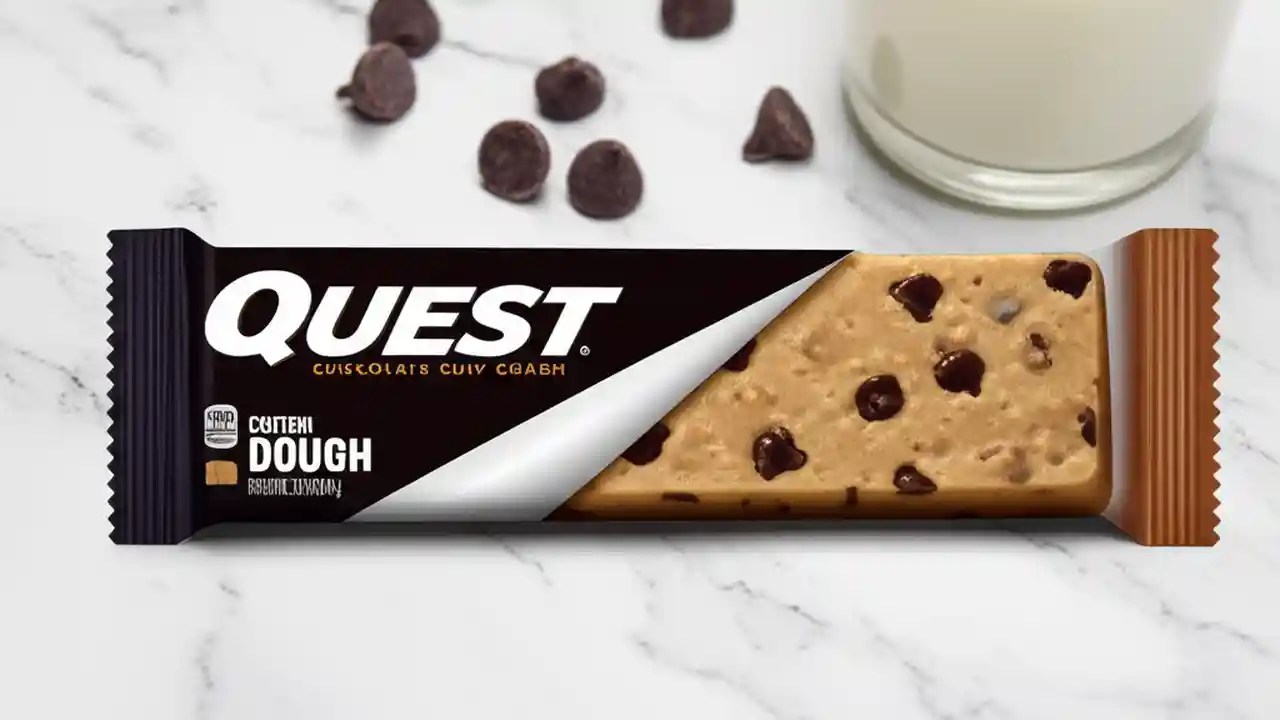 A Quest Chocolate Chip Cookie Dough protein bar unwrapped on a wooden table, illustrating its protein and ingredients.