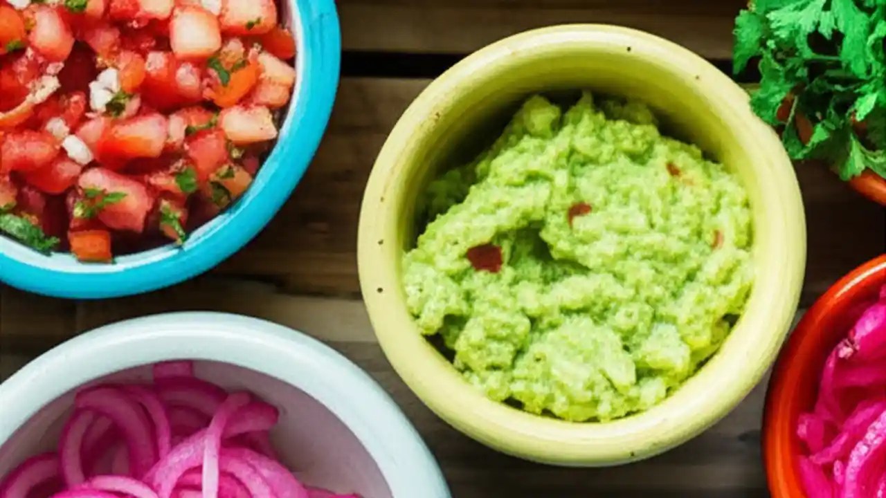 An overhead view of three types of tacos with various toppings like cilantro, onion, slaw, and pineapple, illustrating a guide to what to put on tacos.