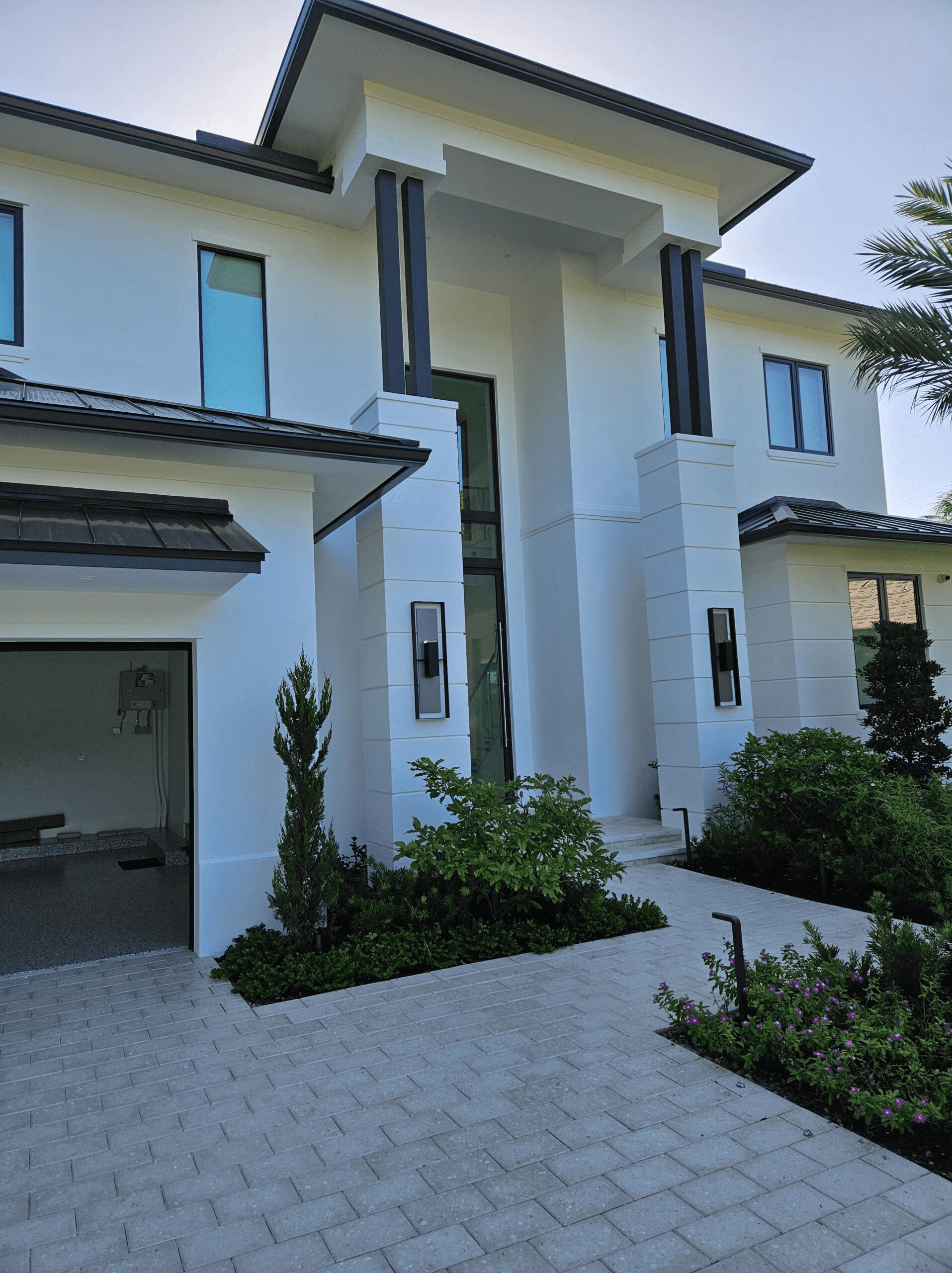 Exterior shot of a modern, Miami style, white home with the sun setting in the background.