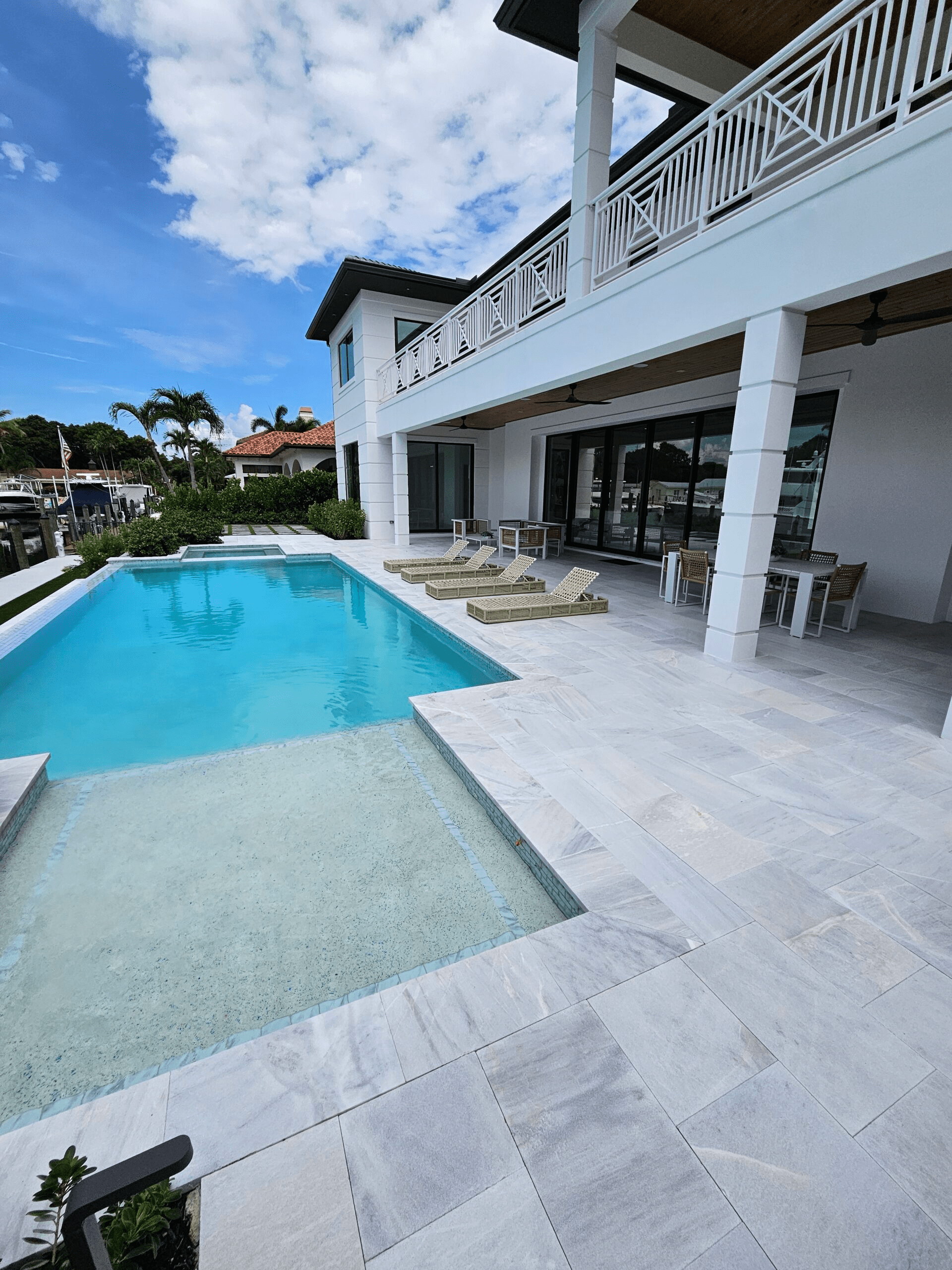 Modern home with crystal clear walk in pool. White stone coping and decking surround the pool.