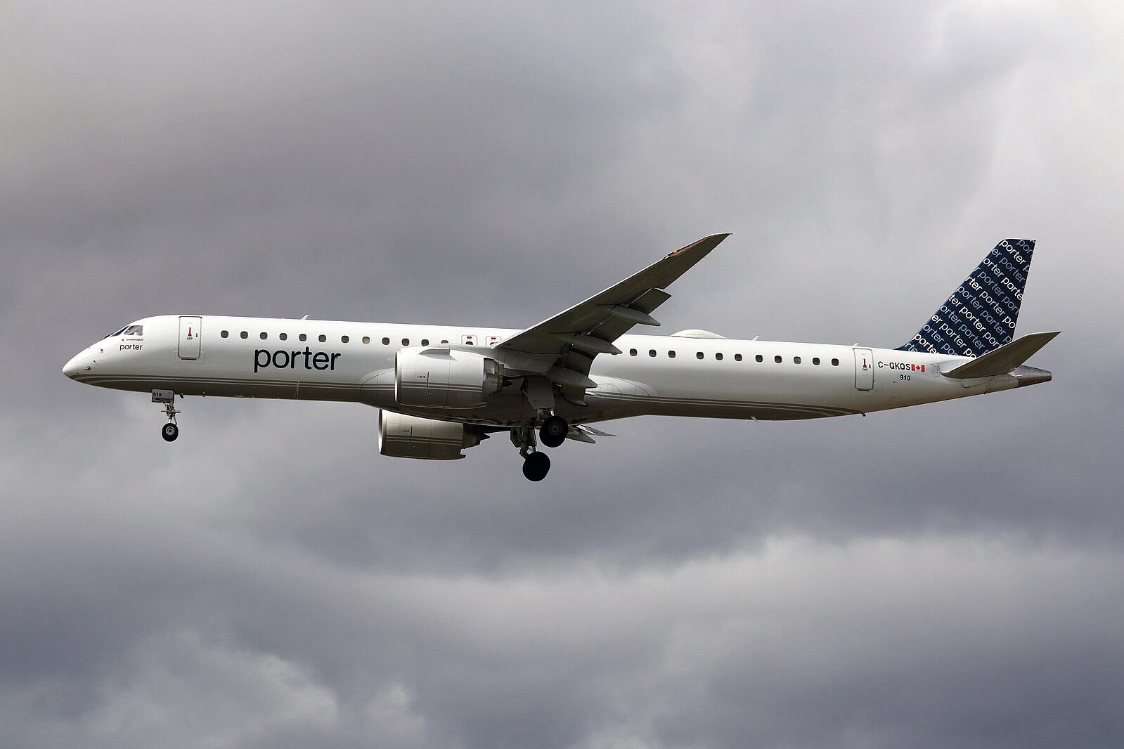 Porter Airlines Embraer E195-E2 in flight against a cloudy sky, with landing gear extended during final approach.