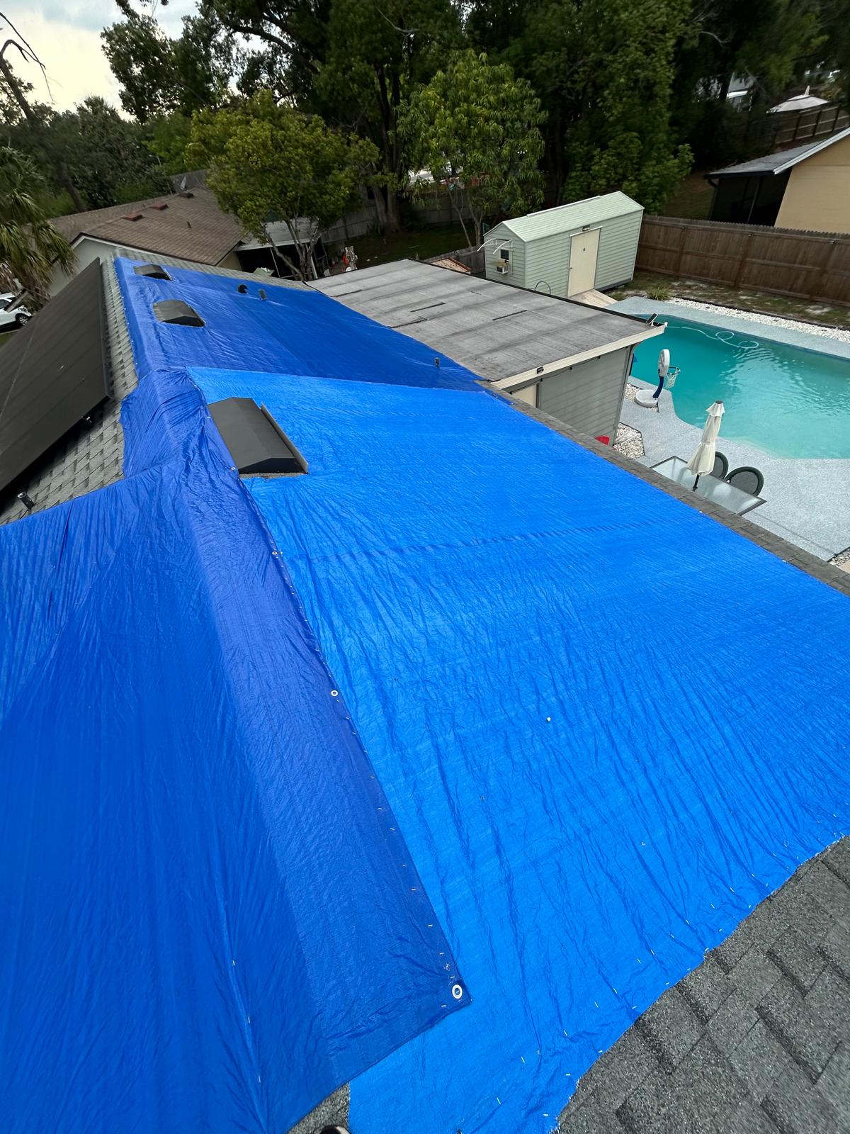 Blue tarp professionally installed on residential roof to prevent water intrusion in Florida