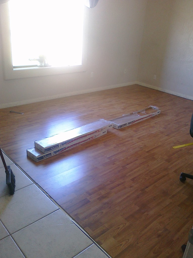 Laminate flooring being installed in a bedroom with spare planks on the floor