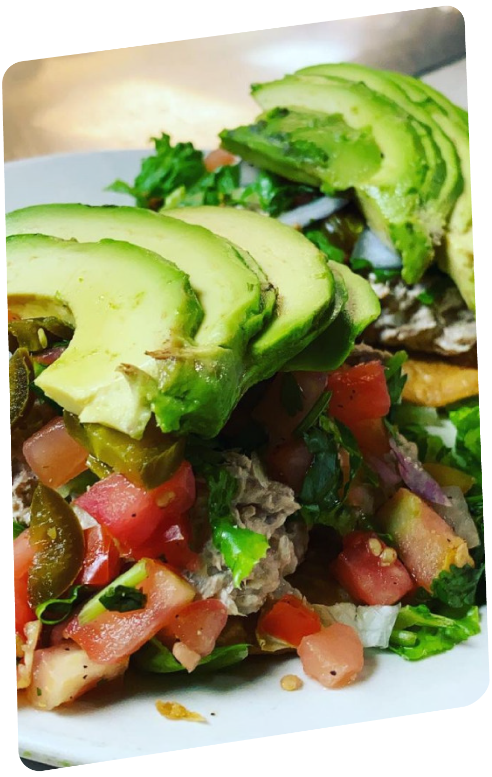 Salad topped with sliced avocado, diced tomatoes, and chopped greens