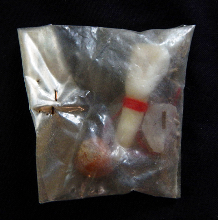 Protection-Mexico-Roman Catholic/Indigenous-1986 coin, red string, rocks, twigs, tooth and seed-2" x 2 1/4"