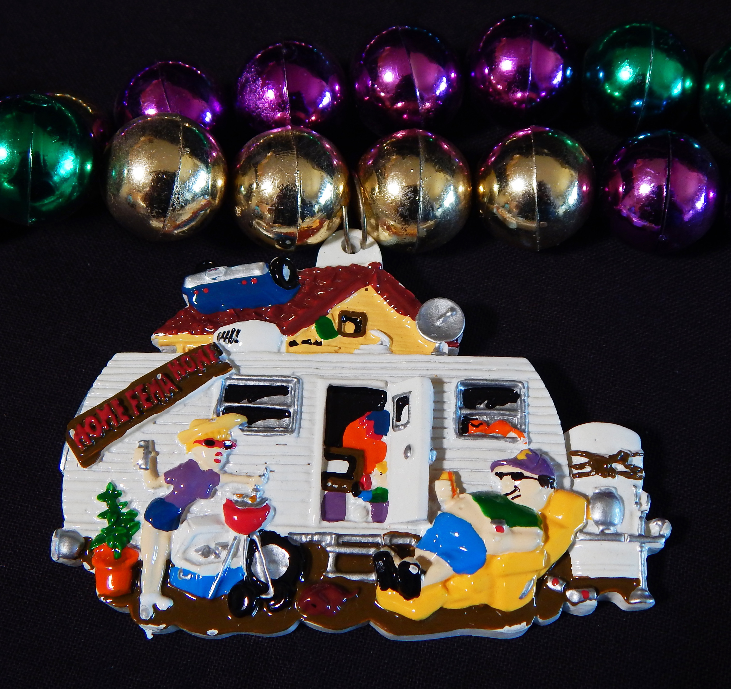 Close-up of house trailer pendant attached to Mardi Gras beads