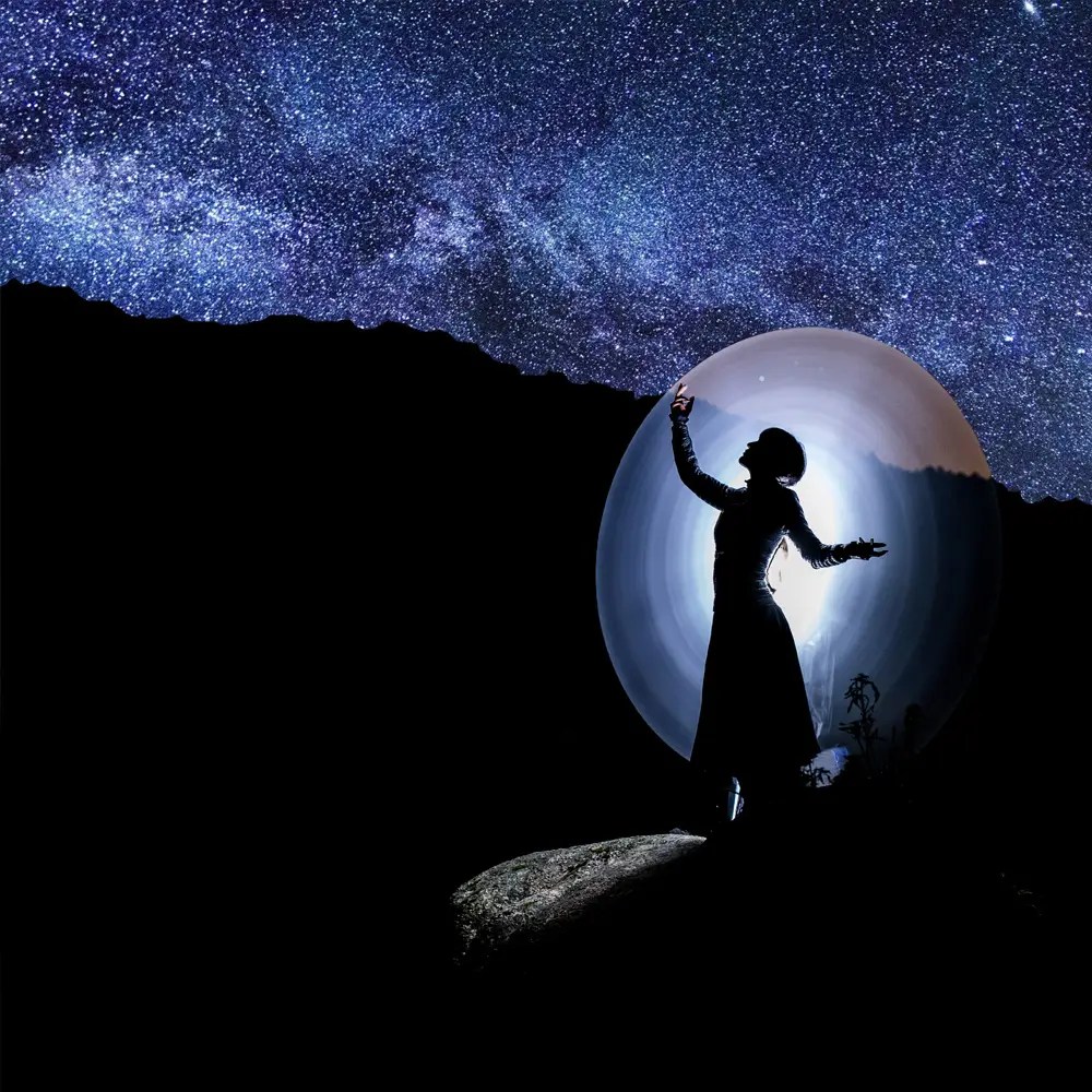 happy traveler hipster girl in hat, standing with backpack and raising hands up in sky in mountains in clouds. space for text. amazing atmospheric emotional moment. travel and wanderlust concept