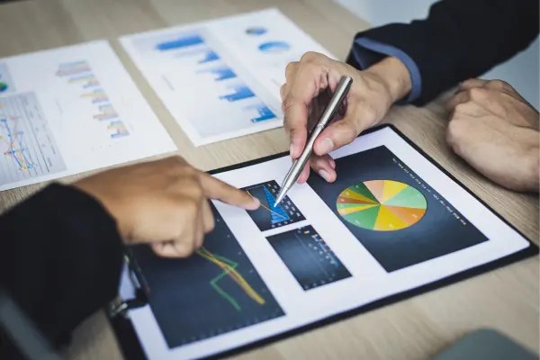 Esta imagem ilustra profissionais examinando gráficos e relatórios para avaliar e discutir diferentes tipos de riscos, reforçando a importância de dados visuais na tomada de decisões e mitigação de incertezas. Ela destaca o valor de análises eficazes