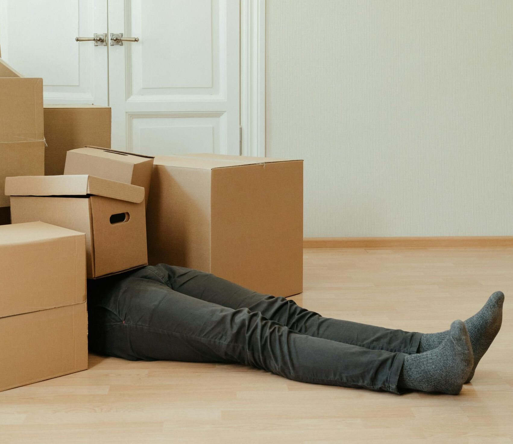 man-lying-tired-under-cardboard-boxes-in-an-empty-room-symbolizing-moving-stress.-4553181-scaled-e17.jpeg