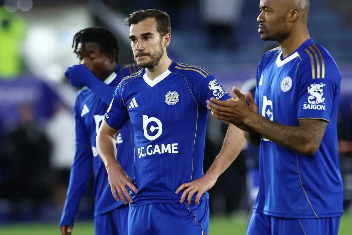 Leicester City players stand with disappointed looks on their faces.