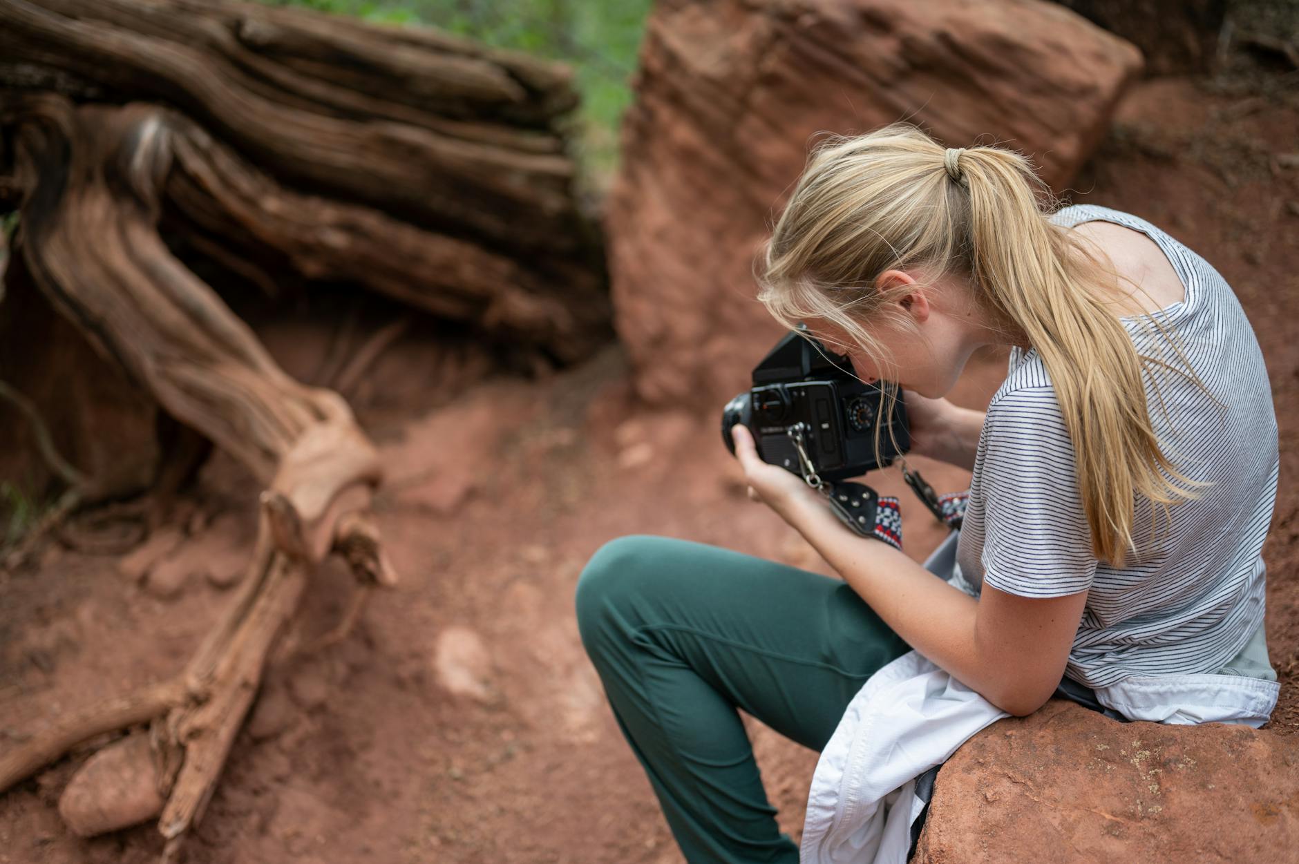 woman sitting on rock taking photos