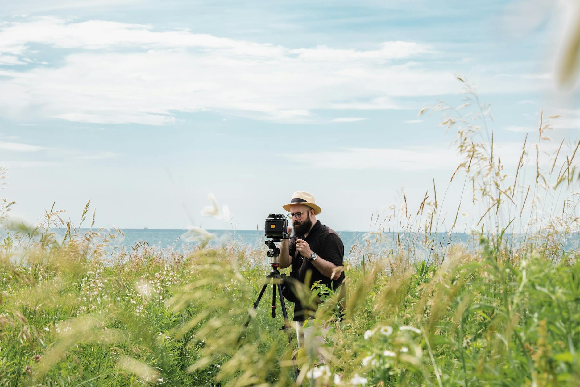 photographer standing with analogue camera on meadow