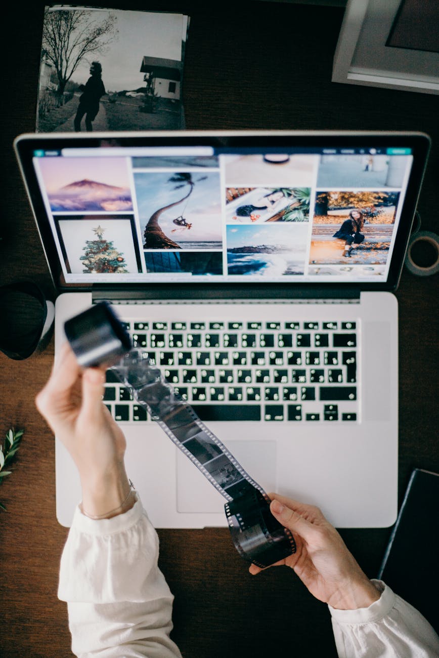 high angle photo of person holding film strip in front of a laptop