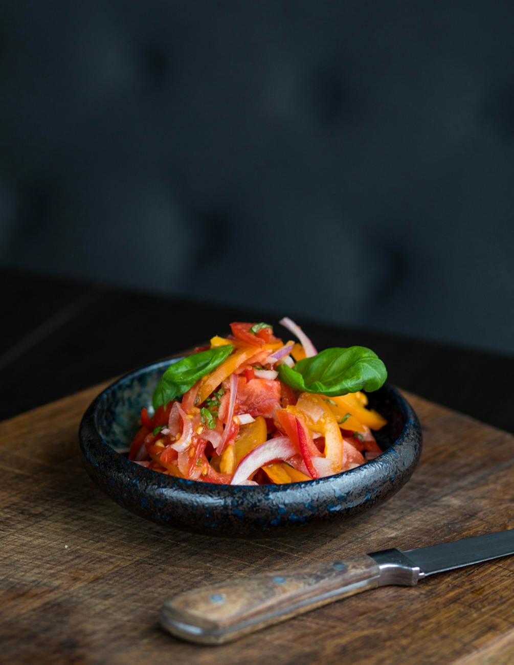 sliced tomato with green vegetables in brown saucer