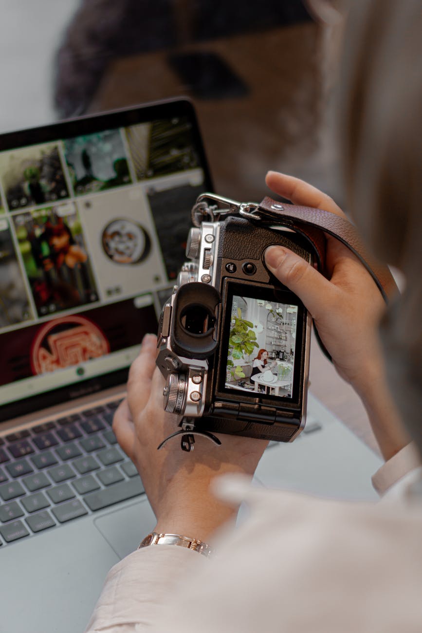 young woman sitting using a laptop and a camera