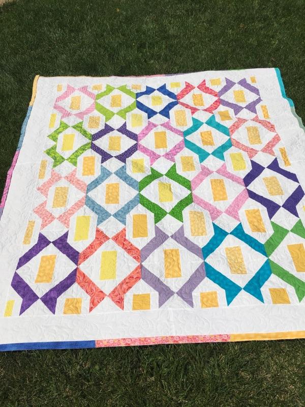 Paper Lanterns Quilt made by Annie Cook of @aecquilts — rainbow lantern blocks with yellow centers on a white background, colorful modern quilt pattern by Four Robbins.
