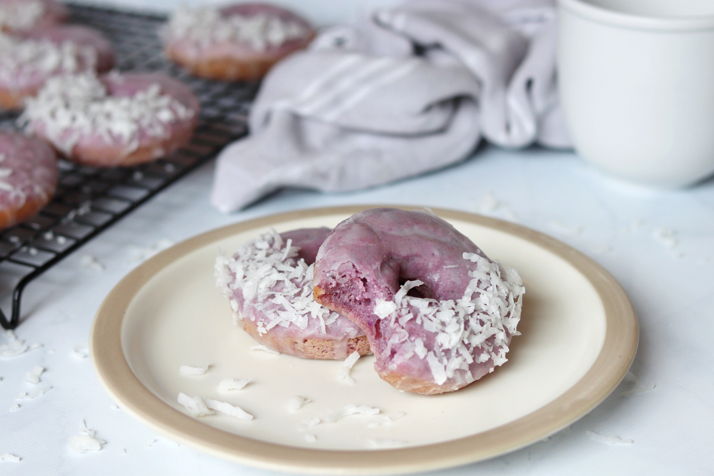 Vibrant ube mochi donut with coconut glaze and topped with shredded coconut