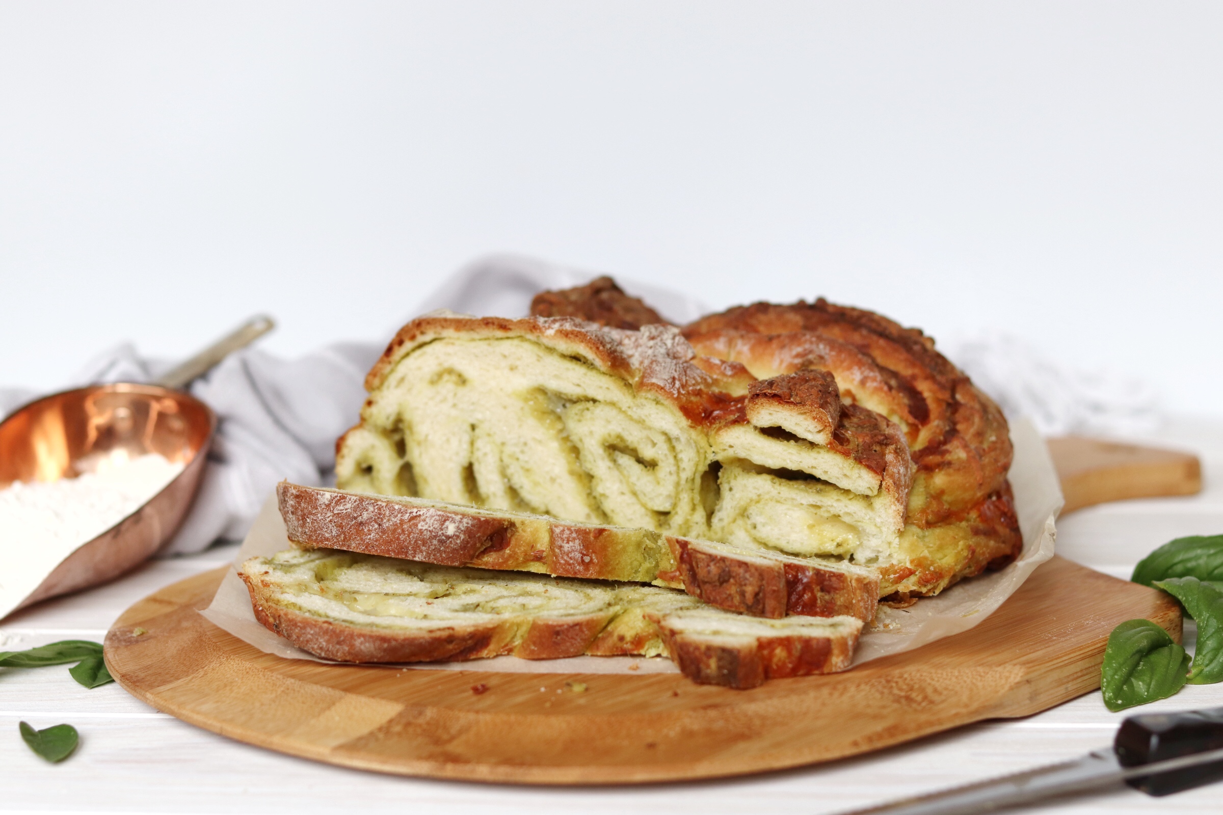 Sliced cheesy pesto swirl bread showing green pesto layers and golden crust