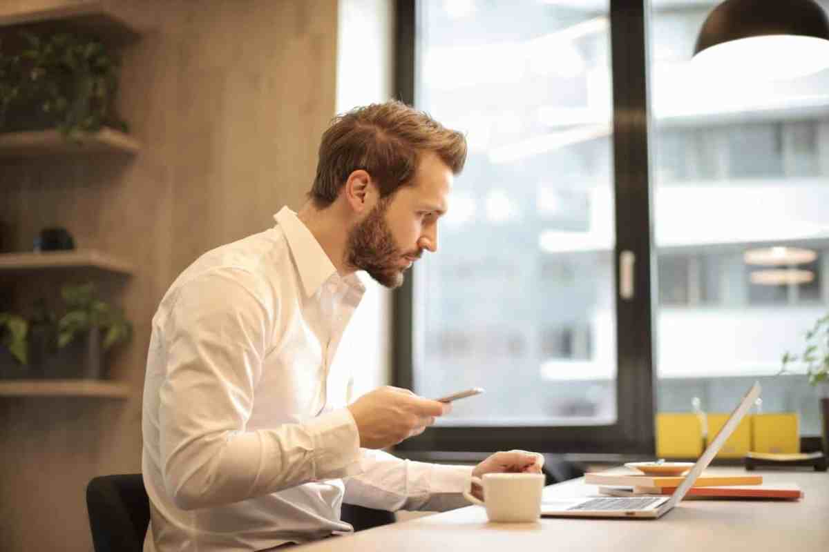 Man checking phone in white shirt — Mindfulness of tech use starts with awareness of phone habits