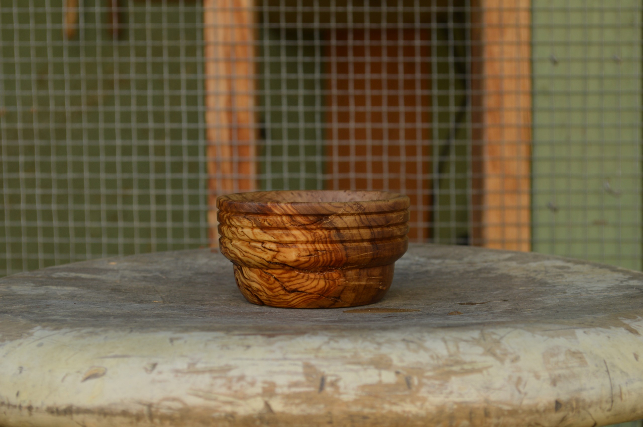 A hand-crafted pinch bowl made from reclaimed California olive wood with horizontal accents around the rim and finished with food-safe, non-toxic oil.