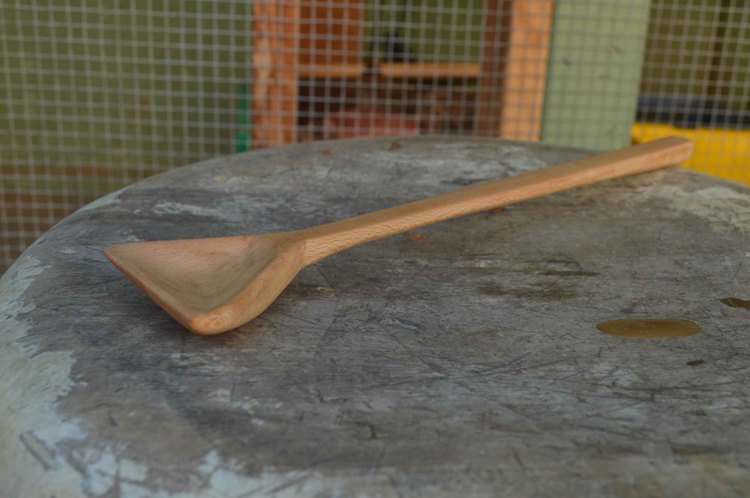 A hand-carved, triangular sycamore cooking spoon hand carved and finished with food-safe oil.